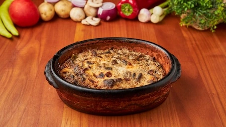 Planinska jagnjetina sa vrganjima zapečena u mleku, poslužena u zemljanoj posudi u Restoranu Gradska Beograd.